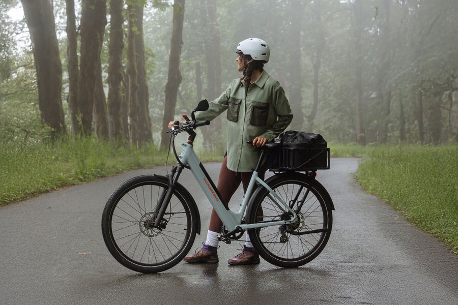 Woman standing with RadKick Arctic Blue electric bike on a misty forest road