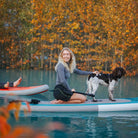 Woman paddleboarding with her dog on an autumn lake using a Synergy board