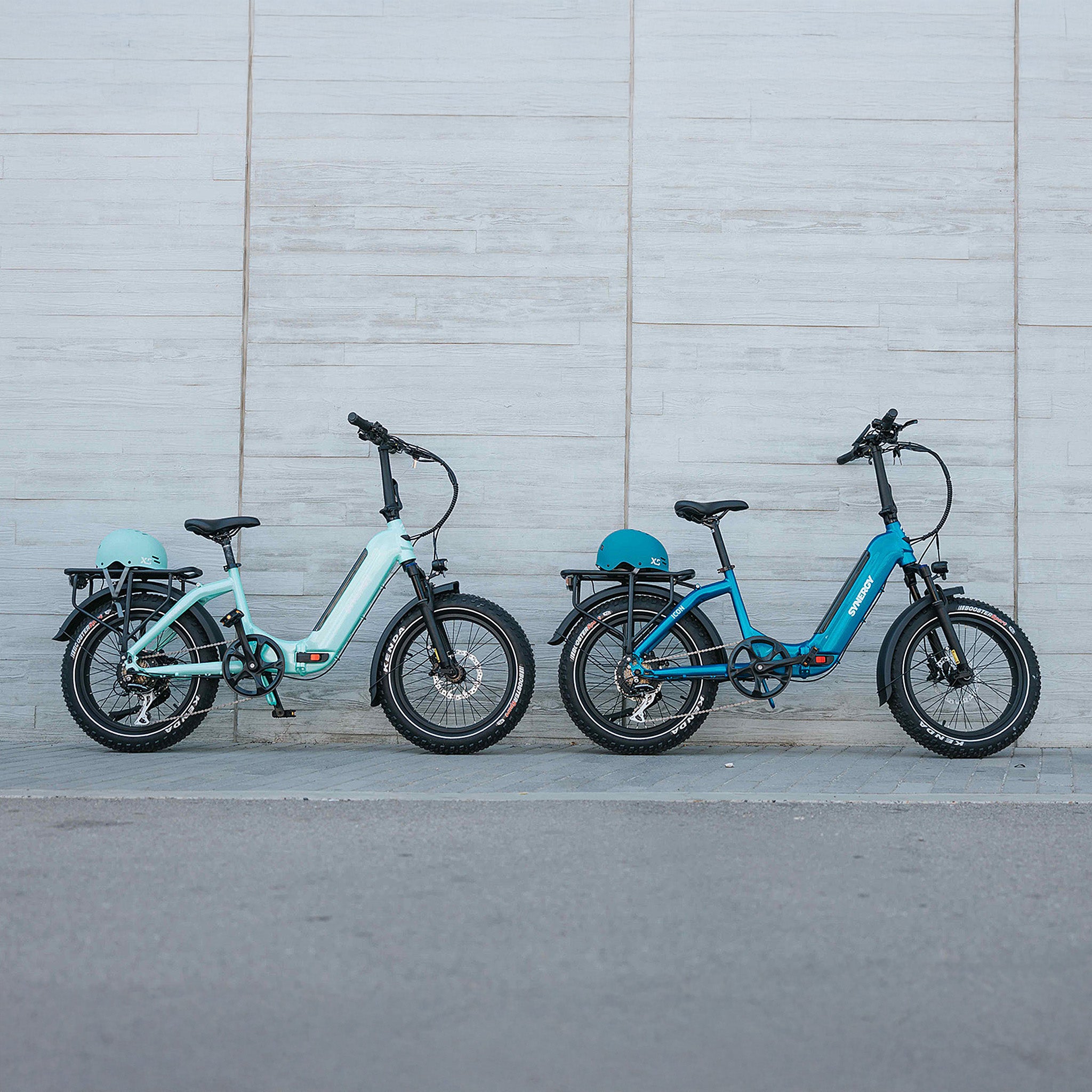 Synergy low-step electric bikes in Blue and Turquoise, parked side-by-side with helmets