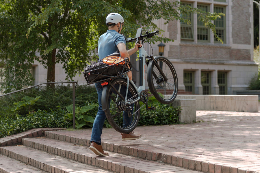 Man carrying RadKick Arctic Blue electric bike up outdoor stairs